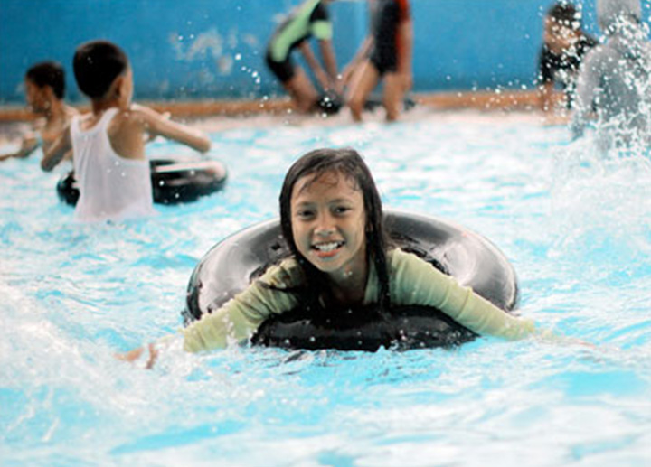 A kid swimming in pool inside a recreational center