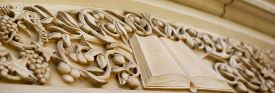 Close-up of a building's exterior, showcasing the design of an opened book carved into the stone