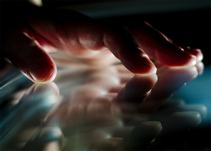 A hand placed against a reflective surface.