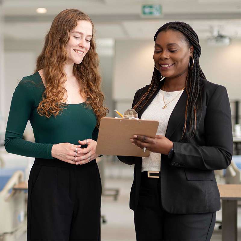 Two graduate nursing students reviewing notes together.