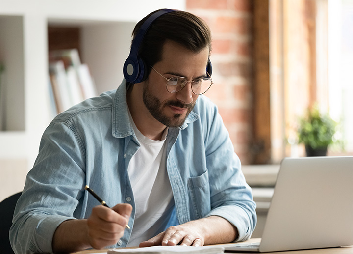 A student attending an online class and taking notes.