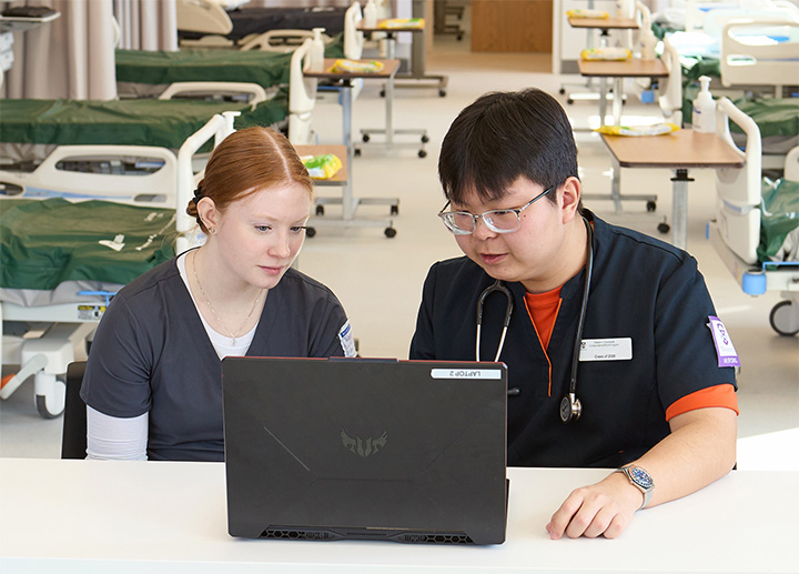 Two nursing students working on a laptop.