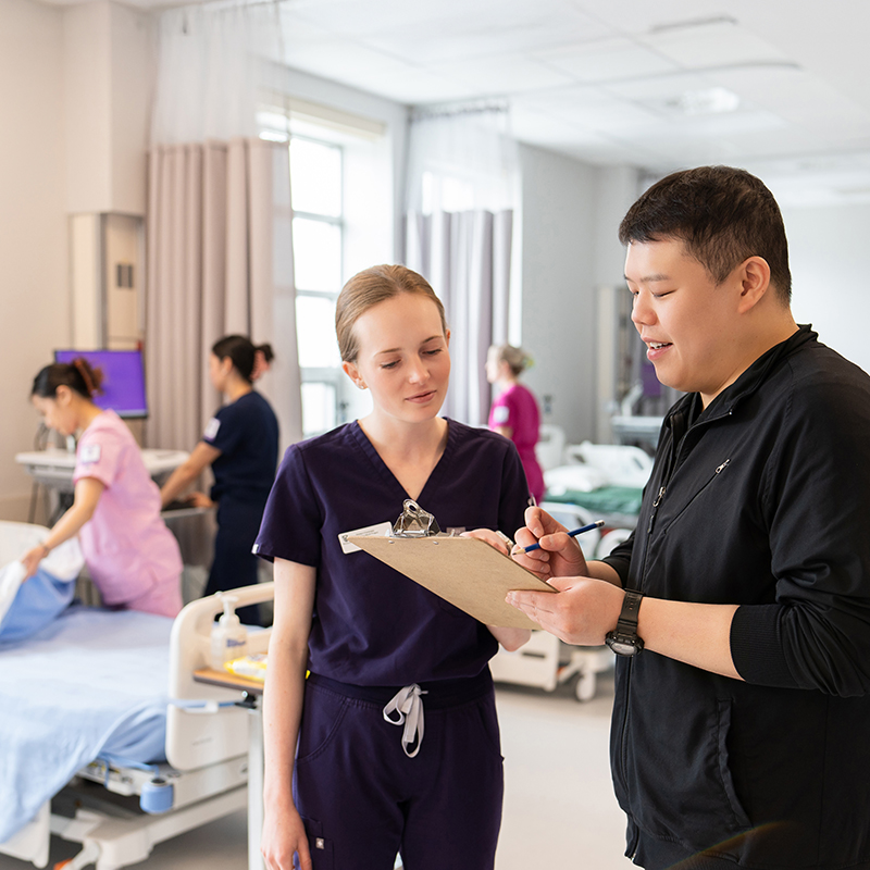 A professor and a nursing student reviewing notes together.