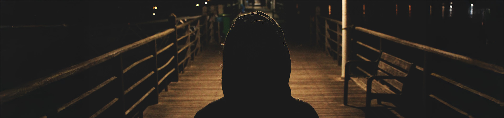 A person standing on a boardwalk at night.