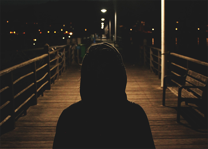 A person standing on a boardwalk at night.