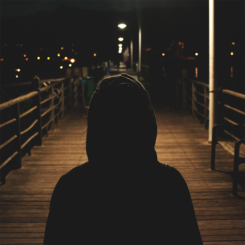 A person standing on a boardwalk at night.
