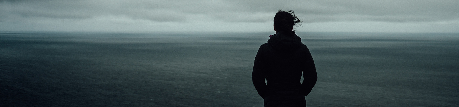 A woman standing and looking out over a large body of water.