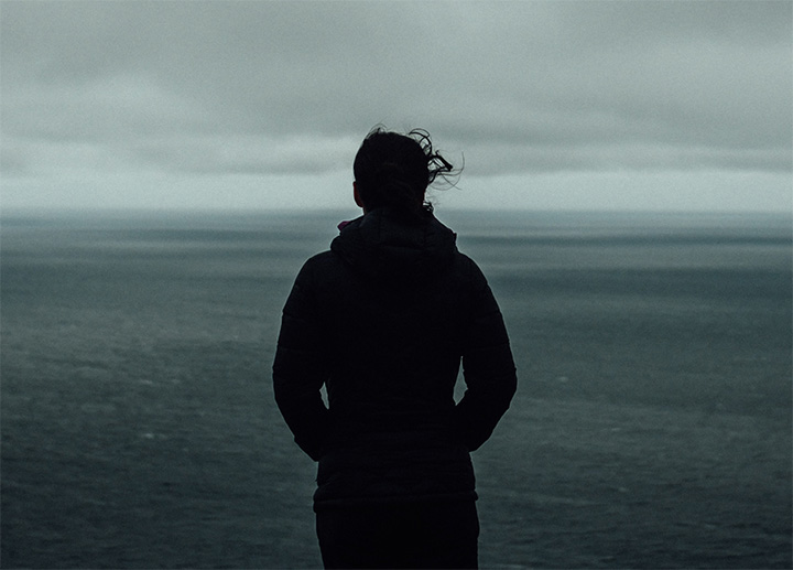 A woman standing and looking out over a large body of water.