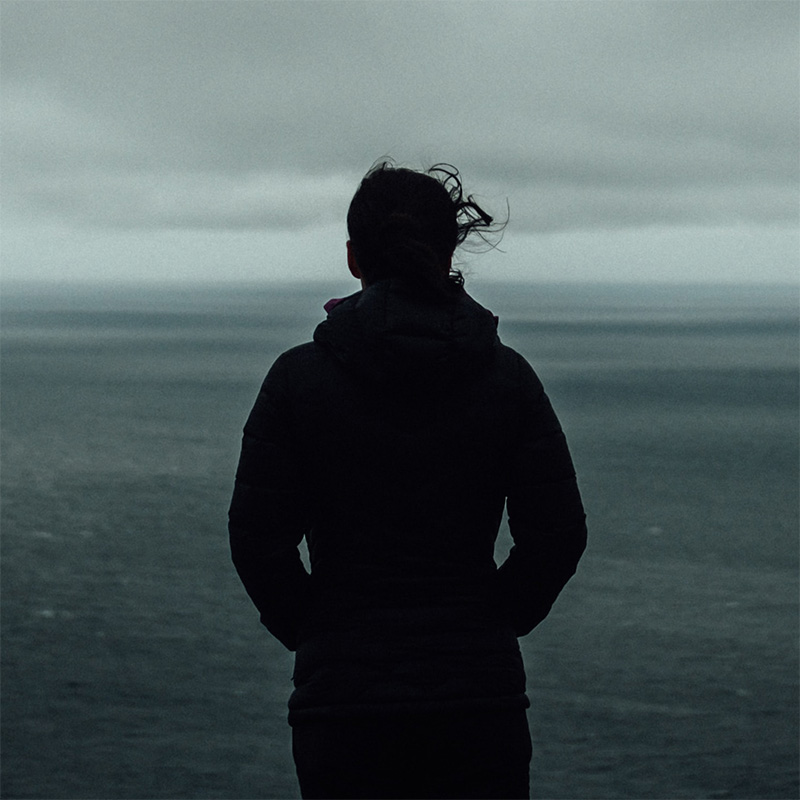 A woman standing and looking out over a large body of water.
