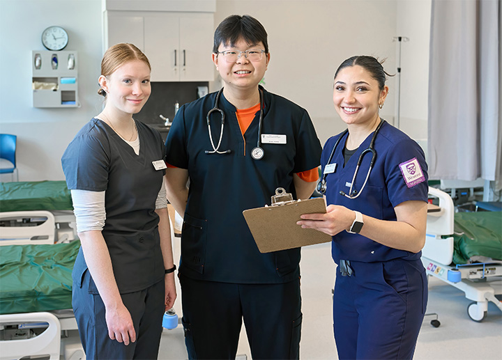 Three nursing students smiling and looking at the camera.