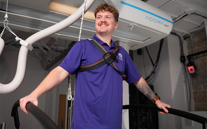 A student standing at some research equipment.