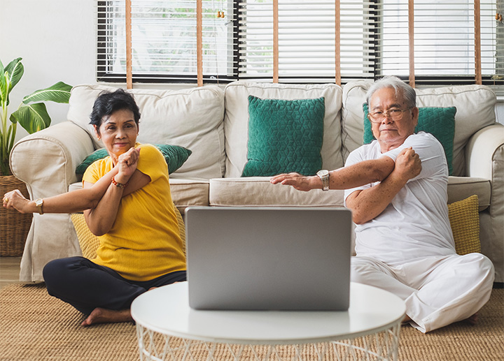 Two people sitting at a computer learning arm exercises.