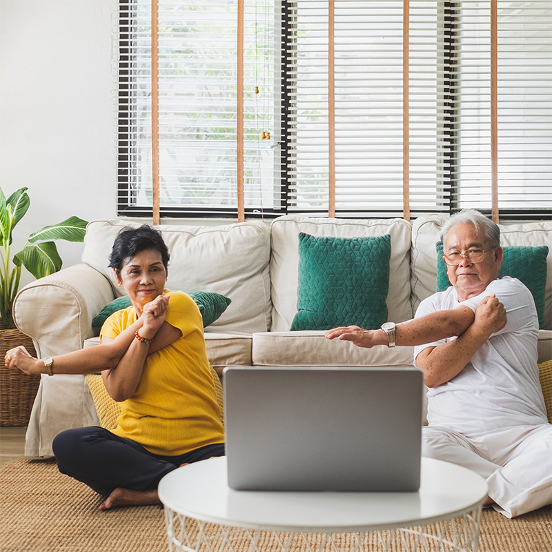 Two people sitting at a computer learning arm exercises.