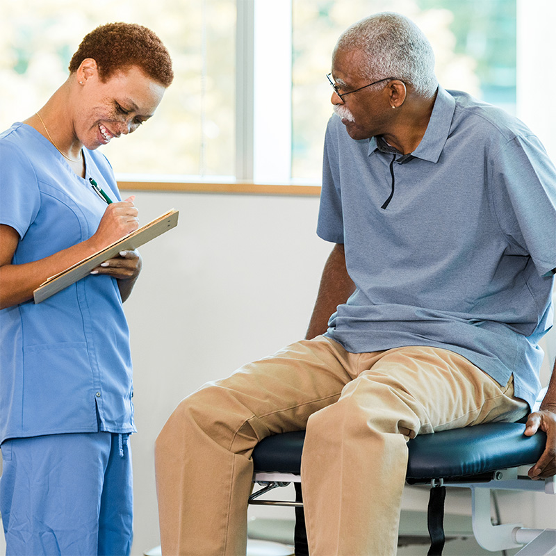 A patient sitting at a clinic speaking with a medical professional.