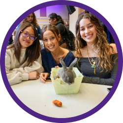 Three students posing with a bunny.