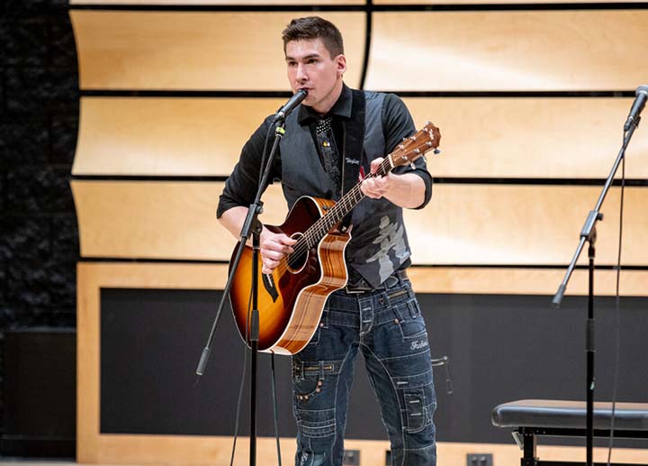 Singer holding an acoustic guitar while performing on stage