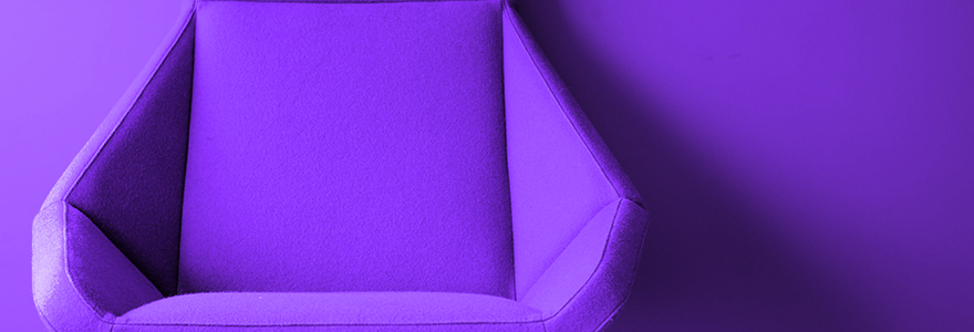 Decorative image of a purple chair set against a purple wall.