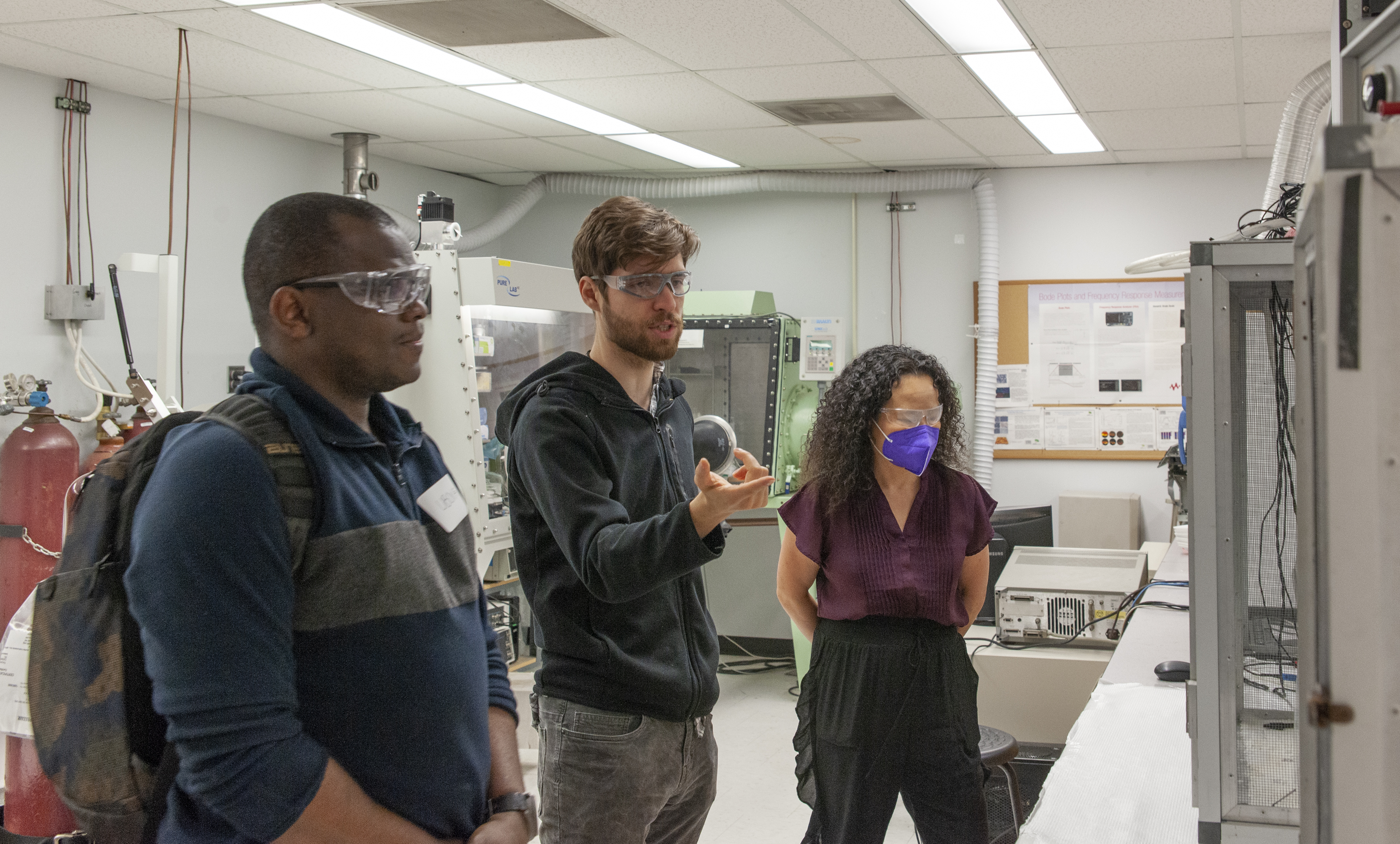 Three people wearing safety equipment in a lab