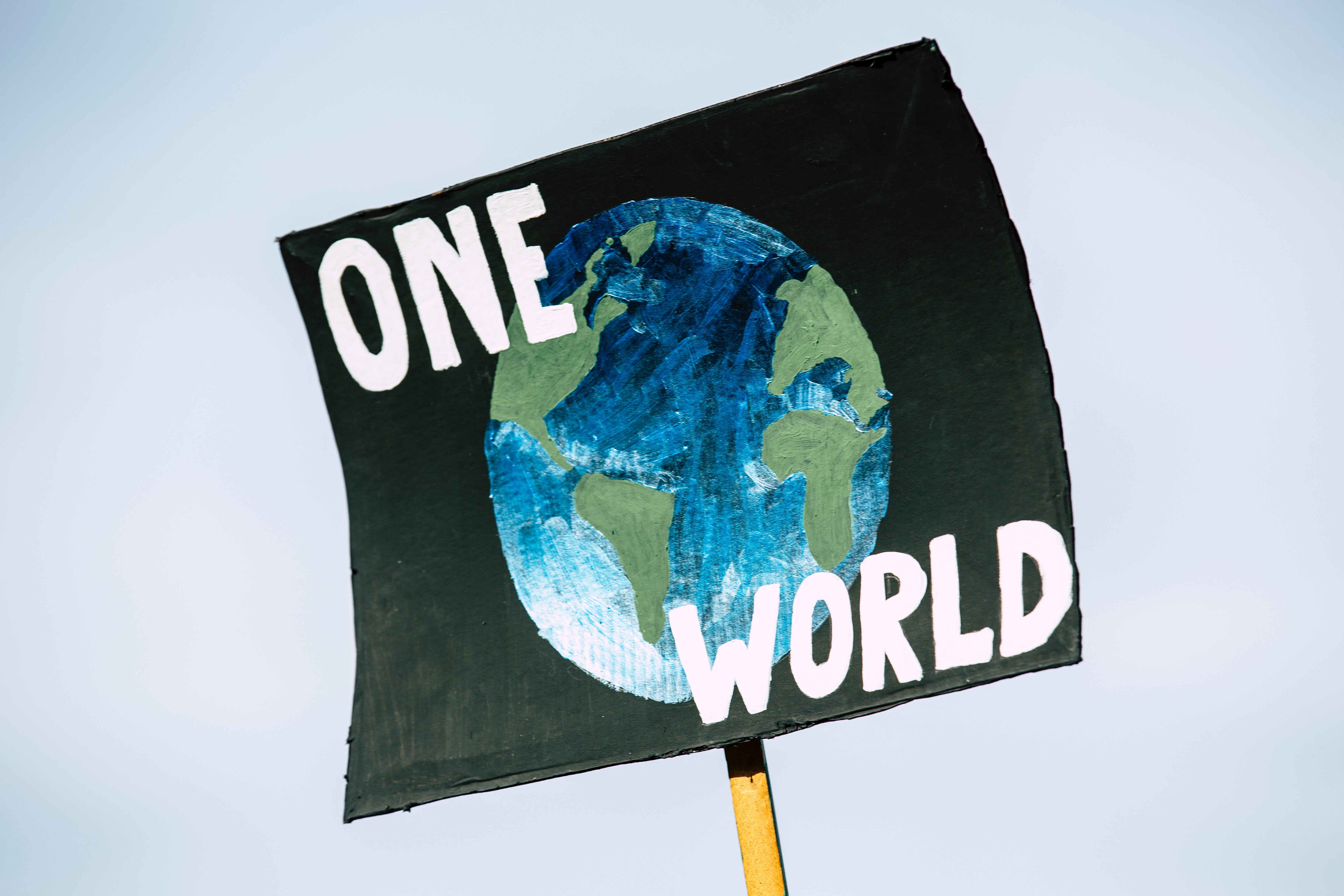 A sign that reads: "One World" with a picture of the earth