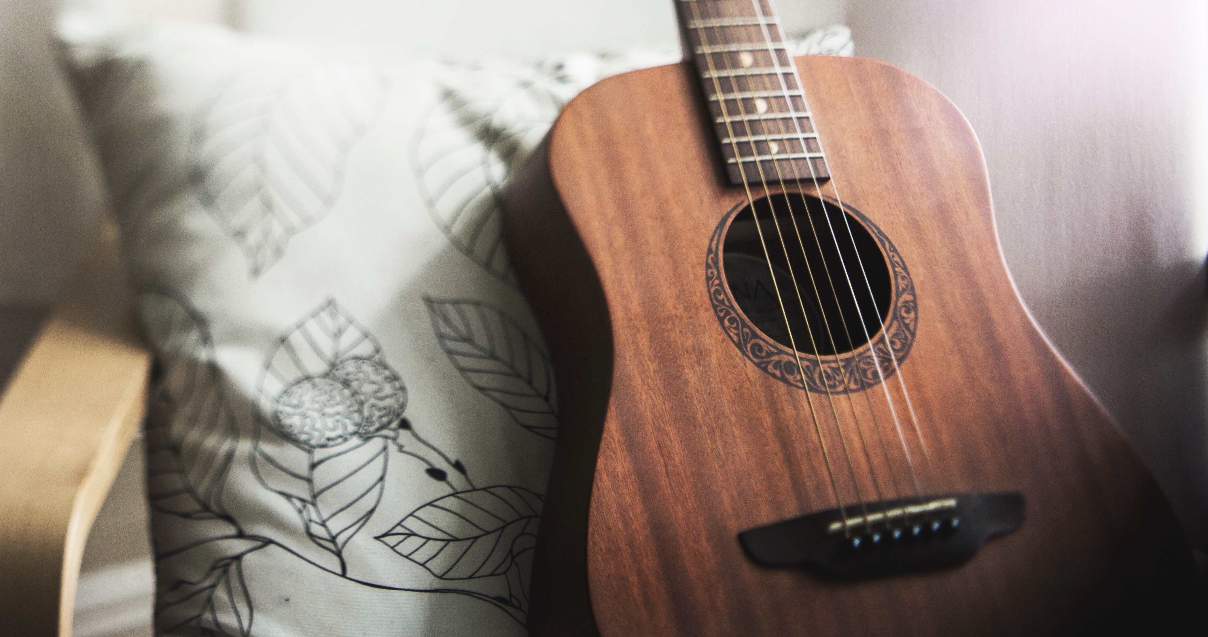 Guitar resting up against a pillow on a chair