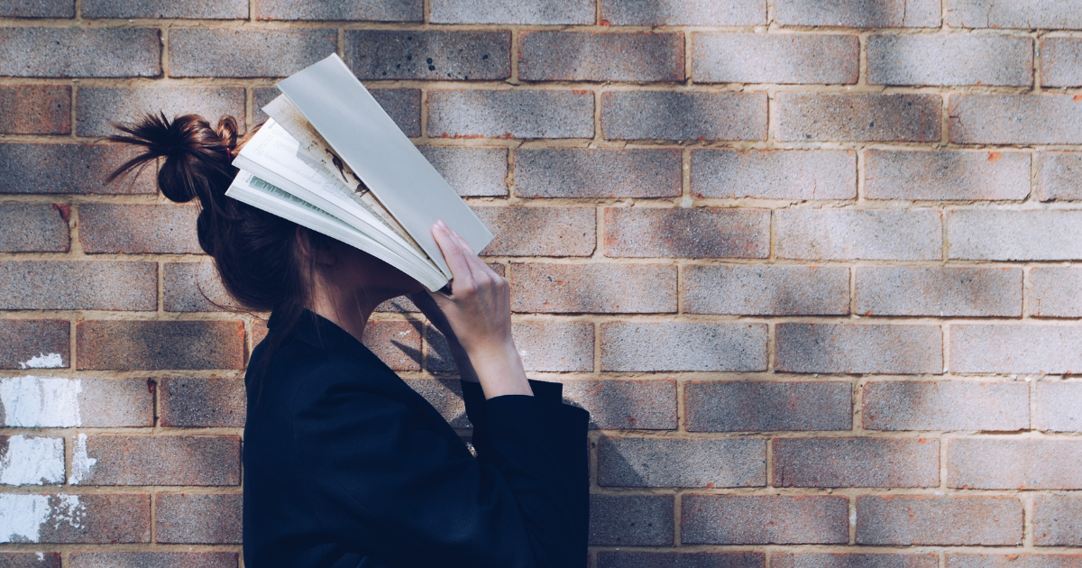 A woman covering her face with a textbook