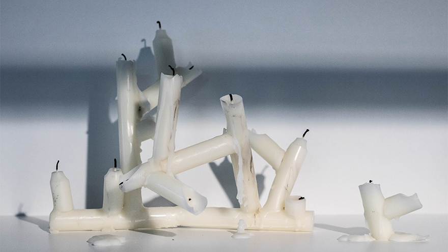 Image of candles melted into sculptures, displayed in a vitrine